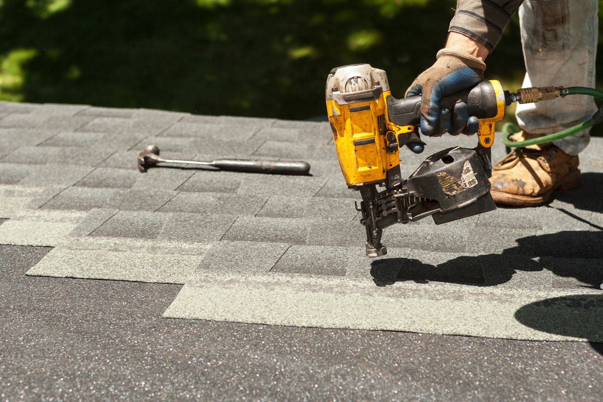 A man operates a nail gun while installing a roof as part of a roof sealing project.