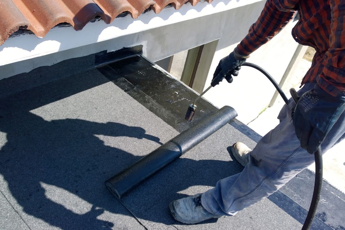 A man sprays water on a roof using a hose, promoting the services of Best Roof Coatings.